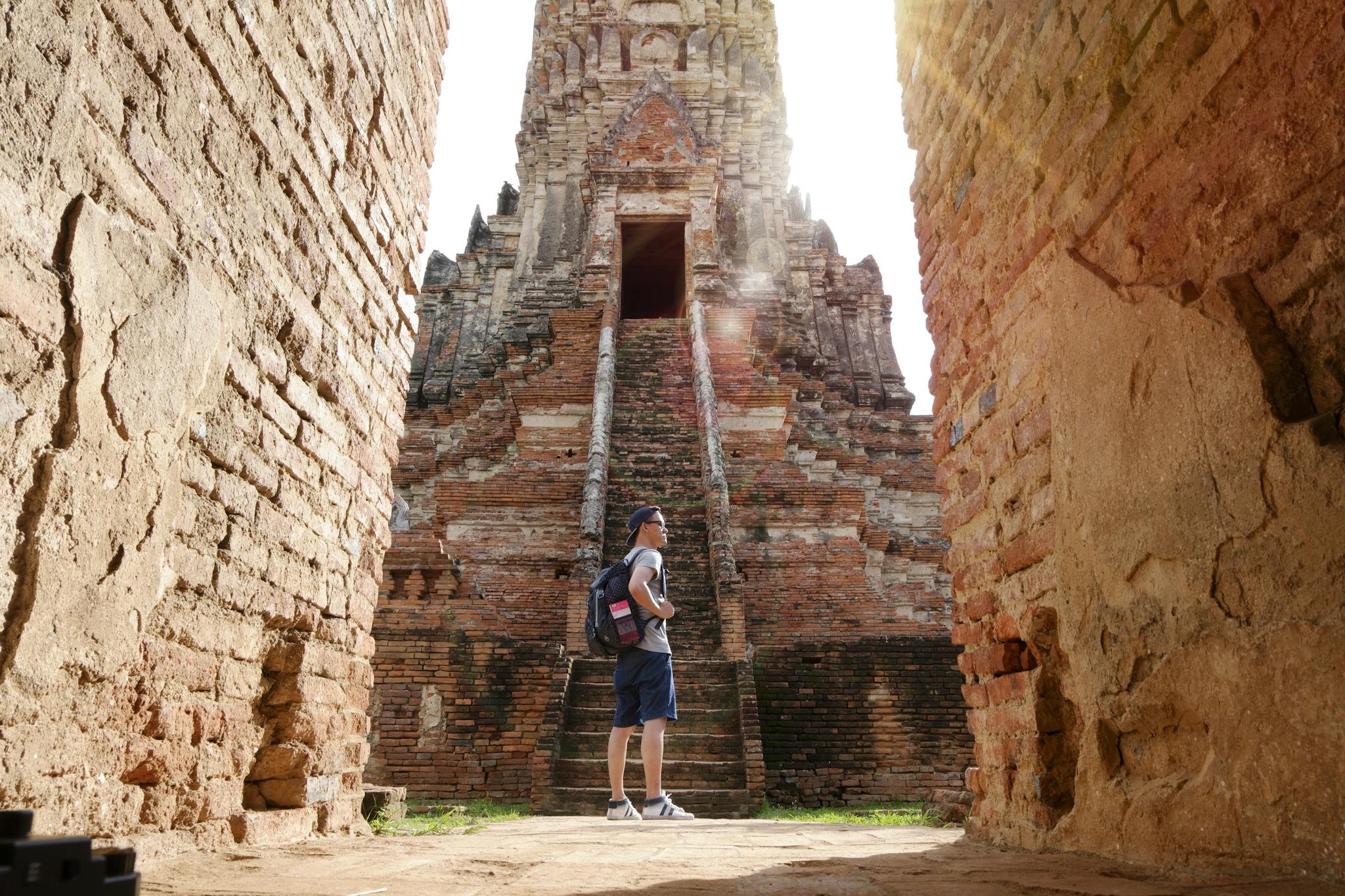 A man with a backpack sightseeing ancient brick temple in summer sunlight.